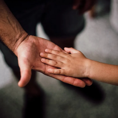 an adult hand holding a child's hand protectively